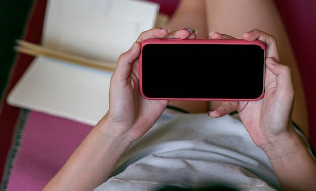 Close-up of a person's hands holding a smartphone displaying a K-drama streaming app, with a background showing a cozy living room.
