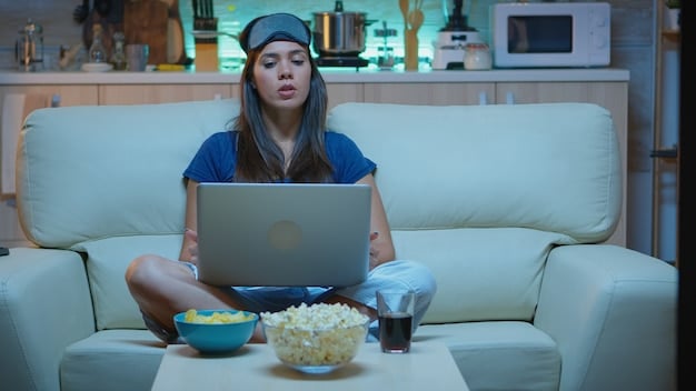 A person relaxing on a couch with a laptop, watching a K-drama. A bowl of popcorn and Korean snacks are on the coffee table.